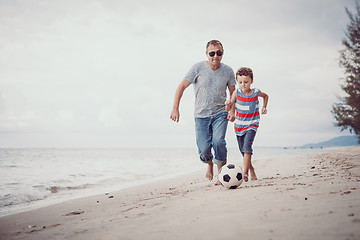 Image showing Father and son playing football on the beach at the day time.