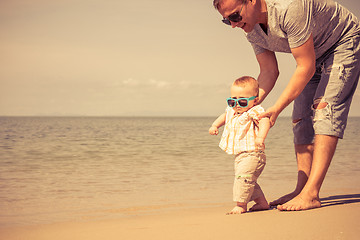 Image showing Father and baby son playing on the beach at the day time.