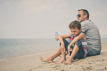 Image showing Portrait of young sad little boy and father sitting outdoors at 