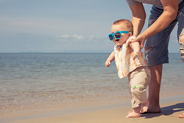 Image showing Father and baby son playing on the beach at the day time.