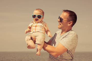 Image showing Father and baby son playing on the beach at the day time.