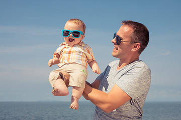 Image showing Father and baby son playing on the beach at the day time.