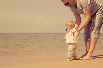 Image showing Father and baby son playing on the beach at the day time.