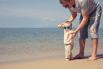 Image showing Father and baby son playing on the beach at the day time.