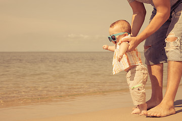 Image showing Father and baby son playing on the beach at the day time.