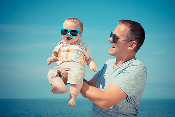 Image showing Father and baby son playing on the beach at the day time.