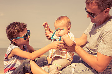 Image showing Father and children  playing on the beach at the day time.