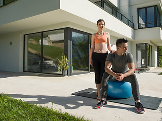 Image showing woman and personal trainer doing exercise with pilates ball