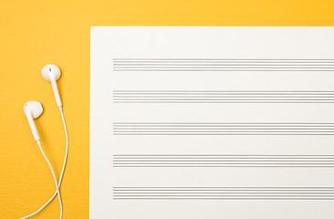 Image showing Earphones and blank music sheet on yellow background