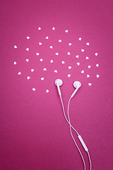 Image showing Earphones and hearts on bright magenta background