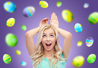 Image showing happy woman making bunny ears over easter eggs