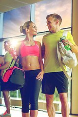 Image showing smiling couple with water bottles in gym