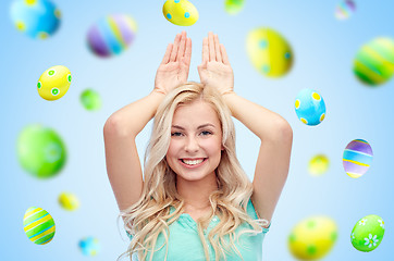 Image showing happy woman making bunny ears over easter eggs