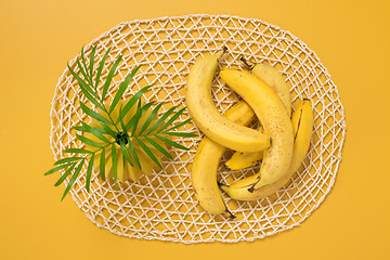 Image showing Ripe bananas and palm leaves on yellow background