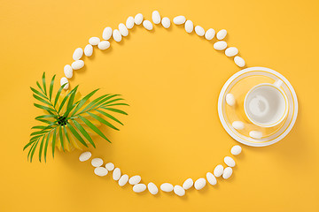 Image showing Frame made of white chocolate, palm leaves and yellow teacup