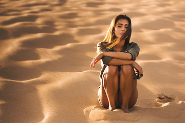 Image showing Young girl sitting on a sand dune