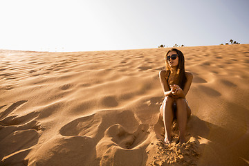 Image showing Young girl sitting on a sand dune
