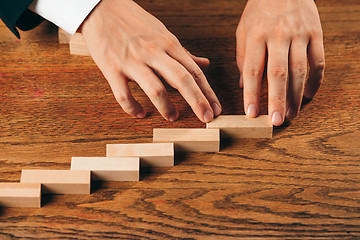 Image showing Man and wooden cubes on table. Management concept