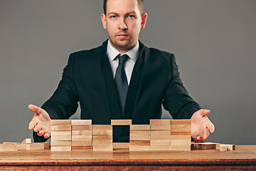 Image showing Man and wooden cubes on table. Management concept