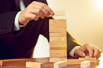 Image showing Man and wooden cubes on table. Management concept