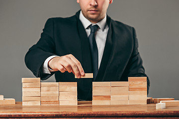 Image showing Man and wooden cubes on table. Management concept