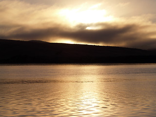 Image showing golden sunrise through clouds over water