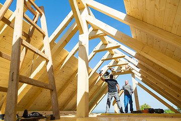 Image showing Builders at work with wooden roof construction.