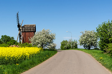Image showing Country road by an old windmill in a colorful spring season land