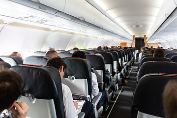 Image showing Interior of large commercial airplane with passengers on their seats during flight.