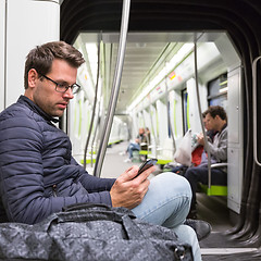 Image showing Male commuter reading from mobile phone screen in metro.