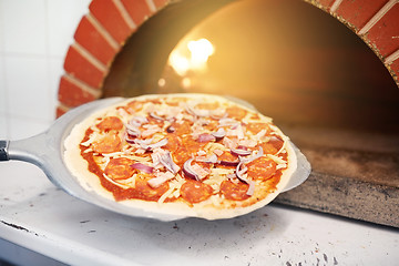 Image showing peel placing pizza into oven at pizzeria