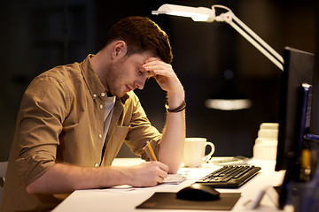 Image showing man with notepad working late at night office