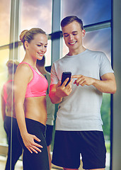 Image showing smiling young woman with personal trainer in gym