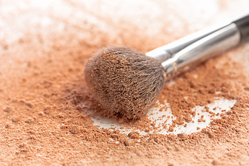 Image showing Close-up of crushed mineral shimmer powder golden color with makeup brush