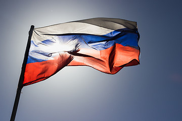 Image showing russian flag flying in slow motion and back lit by the sun.