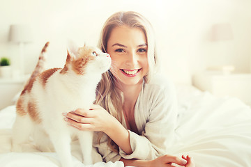 Image showing happy young woman with cat in bed at home