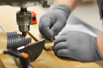 Image showing carpenter with ruler measuring board at workshop