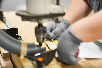 Image showing carpenter with ruler measuring board at workshop