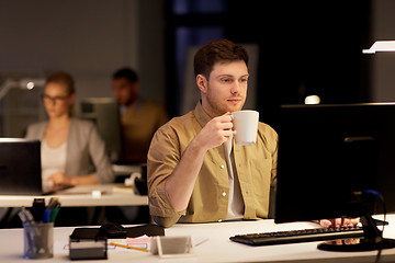 Image showing man with laptop and coffee working at night office