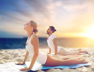 Image showing couple doing yoga and cobra pose on beach