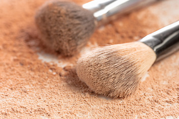 Image showing Close-up of crushed mineral shimmer powder golden color with makeup brush