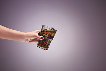 Image showing Drink cola in glass with hand on lilac background.