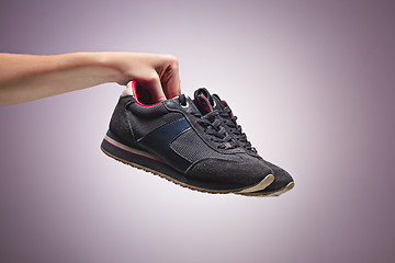 Image showing Hand Holding An Old Dirty Sneaker Shoe