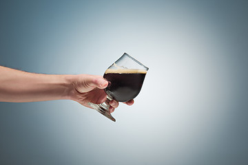 Image showing Closeup of a male hand holding up a glass of beer