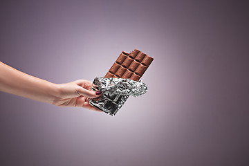 Image showing Hands of a woman holding a tile of chocolate