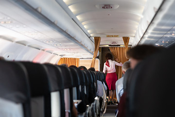 Image showing Interior of commercial airplane with stewardess walking the aisle.