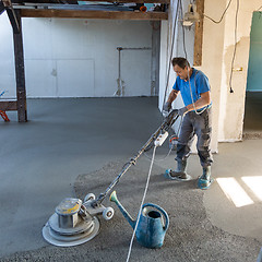 Image showing Laborer polishing sand and cement screed floor.