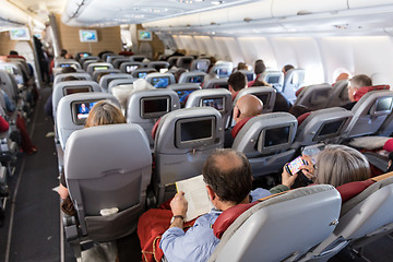 Image showing Interior of large commercial airplane with passengers on their seats during flight.