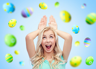 Image showing happy woman making bunny ears over easter eggs