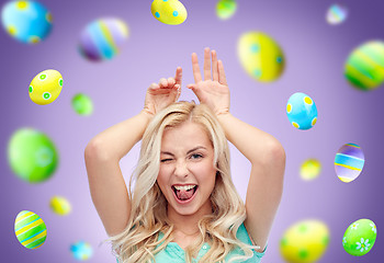 Image showing happy woman making bunny ears over easter eggs